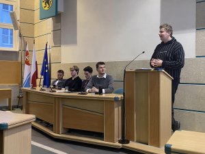 Piątka młodych radnych podczas sesji 11 kwietnia 2023 roku w gdyńskiej sali obrad. Jeden z radnych przy mównicy, czterech za stołem