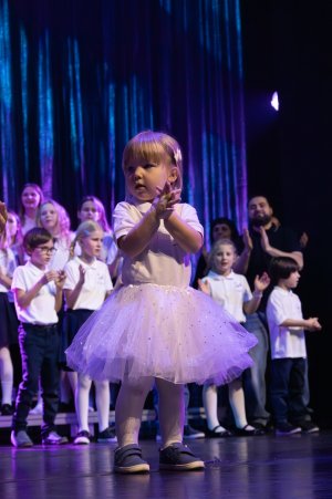 Mała dziewczynka w białym stroju na scenie
