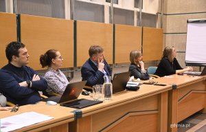 na zdjęciu ludzie słuchający prowadzącej