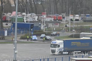 Radiowóz i policjanci stojący przy skrzyżowaniu o ruchu okrężnym
