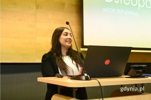 Kobieta stojąca za pulpitem z laptopem