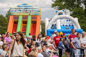 Na pierwszym planie grupa ludzi w różnym wieku na festynie międzypokoleniowym w parku Kilońskim. W tle kolorowe dmuchane zjeżdżalnie // fot. Karol Stańczak
