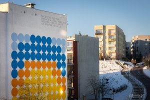 Kolorowe koła na jednym z blok&oacute;w układające się we wsch&oacute;d słońca nad morzem