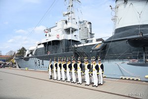 Podchorążowie Akademii Marynarki Wojennej przebrani w historyczne mundury stoją przed okrętem ORP Błyskawica.