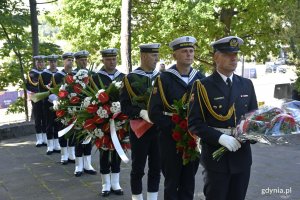Żołnierze Marynarki Wojennej stoją w rzędzie z wieńcami i wiązankami kwiatów w rękach // fot. Magdalena Czernek