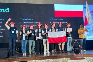 Grupa młodzieży trzmająca polską flagę o medale na scenie