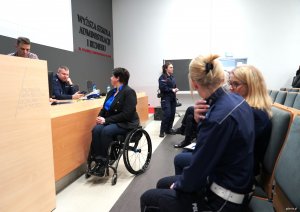 Kobieta na w&oacute;zku inwalidzkim i kobiety w mundurach policyjnych