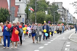 Uczestnicy przemarszu w ramach V Pomorskiego Dnia Seniora idący ul. Świętojańską. W kolorowych strojach i z balonami w rękach