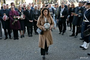 Posłanka Dorota Arciszewska-Mielewczyk składająca znicz pod tablicą pamiątkową, kt&oacute;ra znajduje się na fasadzie Dworca PKP Gdynia Gł&oacute;wna, podczas uroczystości z okazji 87. rocznicy pierwszych wysiedleń Gdynian 