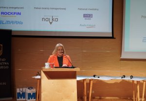 Kobieta w pomarańczowej marynarce na scenie