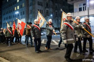 Pochód ludzi ze sztandarami idący ulicami miasta