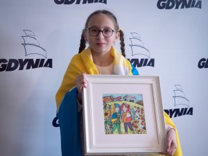 Marta Hrytsaniuk - 9-letnia artystka z Ukrainy owinięta flagą Żytomierza. W ręku trzyma jedną ze swoich prac // fot. Piotr Miszczyk