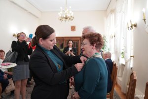 Kobieta przypina medal innej kobiecie