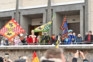 Trzej królowie z flagami i uczestnicy orszaku przed kościołem pw. Najświętszego Serca Pana Jezusa
