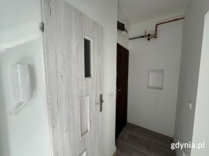 Na zdjęciu widać przedpokój mieszkania komunalnego. Widoczne są rury gazowe oraz drzwi do łazienki.
