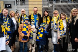 Arkadiusz i Sebastian Kupcewiczowie (w środku) pozują do zdjęcia m.in. z bliskimi i radnymi Norbertem Anisowiczem, wiceprzewodniczącą Rady Miasta Gdyni Mariolą Śrubarczyk-Cichowską, Teresą Bysewską i Moniką Strzałkowską. Symboliczne odsłonięcie tablicy z nazwą placu Janusza Kupcewicza przy Stadionie Miejskim w Gdyni (fot. Kamil Złoch)