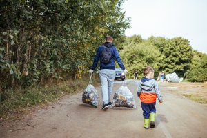 Akcja "Sprzątanie Gdyni 2018". Na pierwszym planie: mężczyzna niosący dwa worki z zebranymi podczas akcji odpadami oraz dziecko idące obok. (fot. Personal PR Sp. z o.o.)