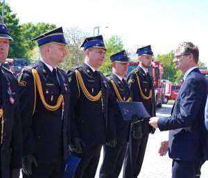 Mężczyzna w garniturze (Rafał Geremek, wiceprezydent Gdyni), podaje dłoń mężczyźnie w mundurze