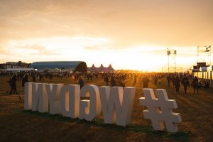 Na pierwszym planie hashtag #wGdyni. Za nim teren i uczestnicy festiwalu w promieniach zachodzącego słońca // fot. Magda Zaklika