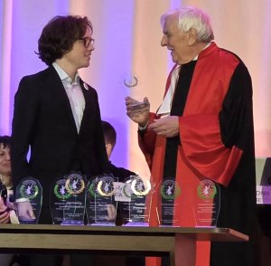 Młody człowiek odbiera nagrodę od mężczyzny w todze