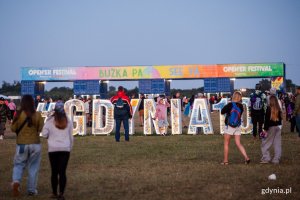 Ludzie podczas festivalu Open'er w Gdyni idący w kierunku bram wyjściowych. Dobrze widoczne napisy "Gdynia 100" i "Bużka, pa".