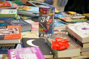 Puszka Wielkiej Orkiestry Świątecznej Pomocy wśr&oacute;d książek udostępnionych na charytatywny kiermasz 