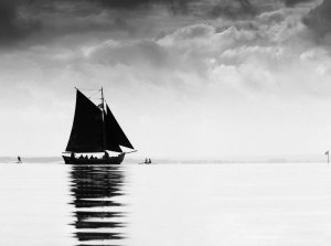 Czarno-białe zdjęcie przedstawiające żaglówkę na powierzchni morza