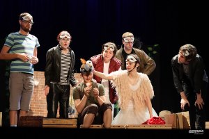 Grupa młodziezy na scenie teatru w przebraniach gołębi.