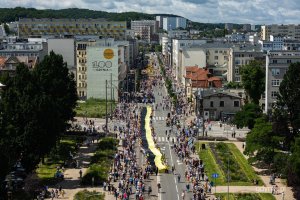   Ujęcie z drona na ul. 3 maja w Gdyni, po lewej stronie budynek z muralem "100 Gdynia. Zaczeło się od morza", po prawej tłum idący z czarno-ż&oacute;łtą flagą po ulicy