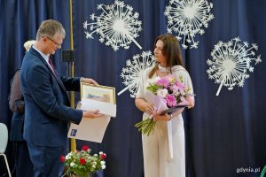 Wiceprezydent Gdyni Rafał Geremek wręczający pamiątkową akwarelę Joannie Zarzyckiej &ndash; dyrektorce Szkoły Podstawowej nr 11 