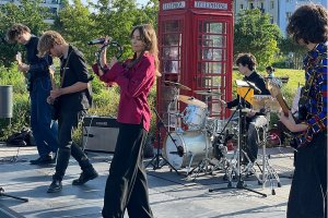Grupa młodych ludzi grających na instrumentach, w pierwszym planie dziewczyna z tamburynem i chłopak z gitarą, w tle perkusita i dwóch gitarzystów w Parku Centralnym w Gdyni.