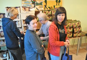 na zdjęciu uśmiechnięci wolontariusze pakują paczki
