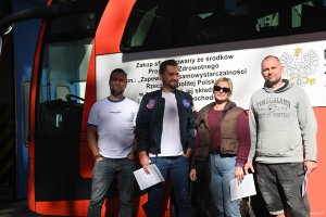 Trzech mężczyn i kobieta na tle ambulansu do pobierania krwi