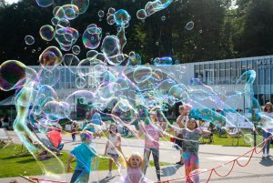 Grupa dzieci bawi się na placu Grunwaldzkim. Otaczają je bańki mydlane. W tle muszla koncertowa // fot. Anna Rezulak