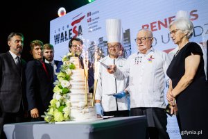 Lecha Wałęsa kroi urodzinowy tort podczas spotkania w Europejskim Centrum Solidarności. Obok niego stoją: żona - Danuta Wałęsa, cukiernicy i goście
