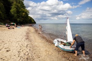 Ludzie plażują na plaży, mężczyzna szykuje na brzegu łódź.