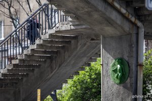 Zielona rzeźba małego dziecka na filarze kładki dla pieszych.
