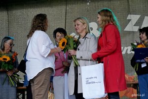 Beata Zastawna &ndash; przewodnicząca Rady Miasta Gdyni i Hanna Niedźwiecka-Pasternak &ndash; zastępca naczelnika Wydziału Ogrodnika Miasta wręczają nagrodę jednej z uczestniczek konkursu &bdquo;Gdynia w kwiatach&rdquo;