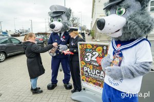 Kobieta w mundurze marynarskim i dwie osoby przebrane za zwierzęta zbierają datki na WOŚP na ulicy.