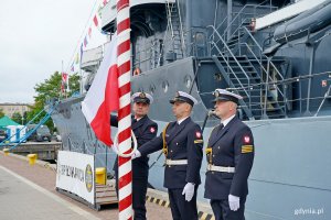 Poczet flagowy podnoszący biało-czerwoną flagę na maszt podczas uroczystości przekazania obowiązk&oacute;w dow&oacute;dcy COM - DKM 