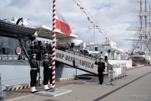 Poczet flagowy wciąga na maszt biało-czerwoną flagę podczas uroczystości z okazji święta 43. Bazy Lotnictwa Morskiego i Dywizjonu Okrętów Bojowych. Za nimi okręt-muzeum ORP "Błyskawica"