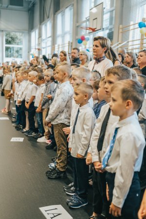 Elegancko ubrane dzieci z klas pierwszych w sali gimnastycznej