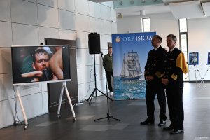 Dwaj mężczyźni w mundurach, w tle fotografie