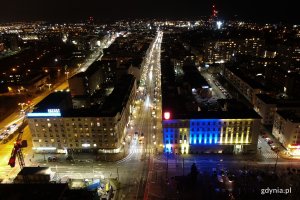 Budynek Urzędu Miasta Gdyni podświetlony wieczorem niebiesko-żółtymi światłami.