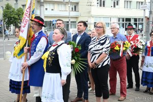 Osoby w ludowych strojach z kwiatami