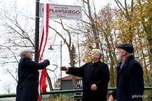 Trzy osoby odsłaniają tablcę z nazwą ulicy.