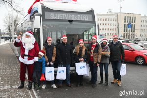 Mikołaj i jego pomocnicy przy autobusie z napisem: święty Mikołaj