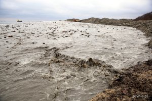 Woda płynie z rury na plaży.