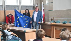 Mężczyzna w garniturze i kobieta z flagą UE.