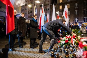 Mężczyzna składający kwiaty przed pomnikiem